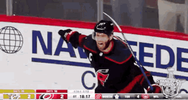 a hockey player is celebrating a goal in front of a banner that says na fede