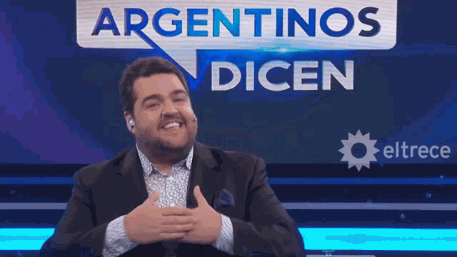 a man stands in front of a sign that says argentinos dicen