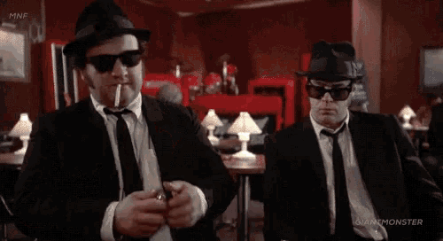 two men in suits and hats are smoking cigarettes and saying we got an understanding ..