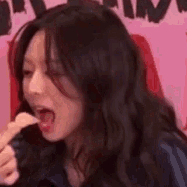 a close up of a woman 's face with her mouth open and her finger in her mouth .