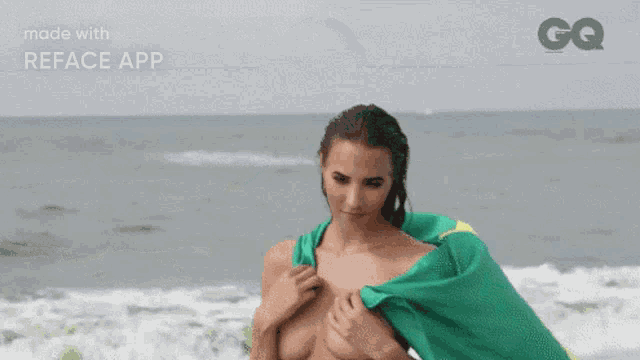 a naked woman holding a green and yellow towel on a beach with a gq logo in the background