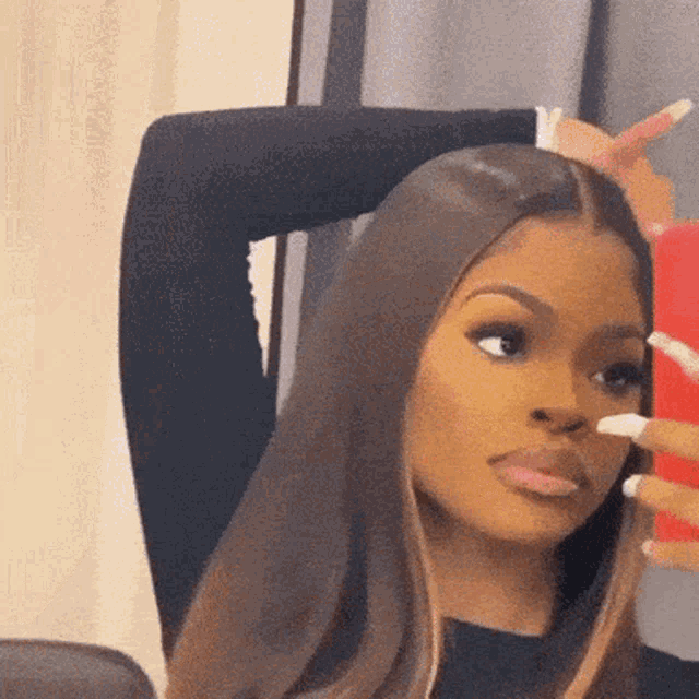 a woman is taking a selfie in front of a mirror with her hand on her head .