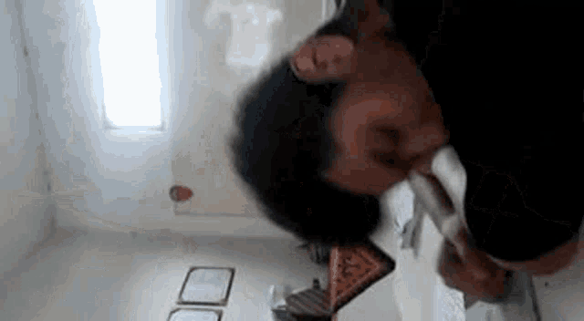 a man is standing in a room with his head on a table and talking on a phone .