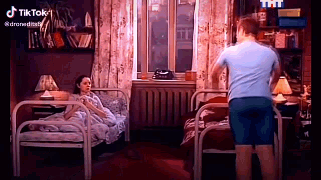 a man is standing next to a woman laying in a bed .