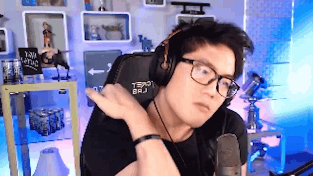 a man wearing headphones and glasses is sitting in front of a microphone and a sign that says " yaw "