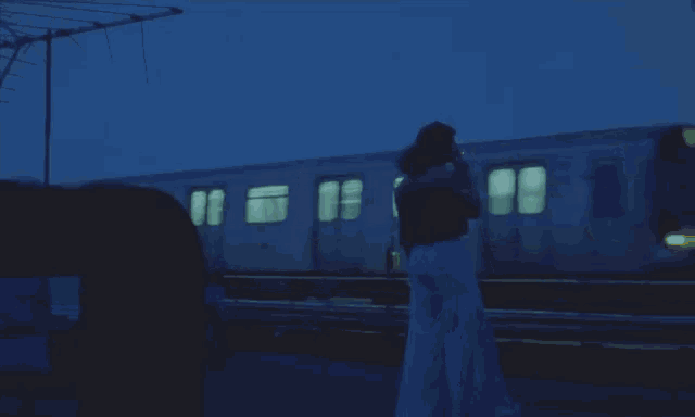 a woman stands in front of a train that has the word subway on the front