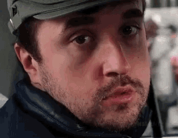 a close up of a man wearing a hat and a beard .