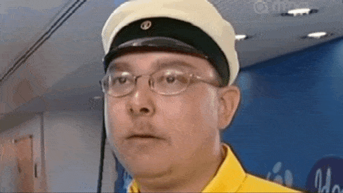 a man wearing glasses and a hat with a letter b on it