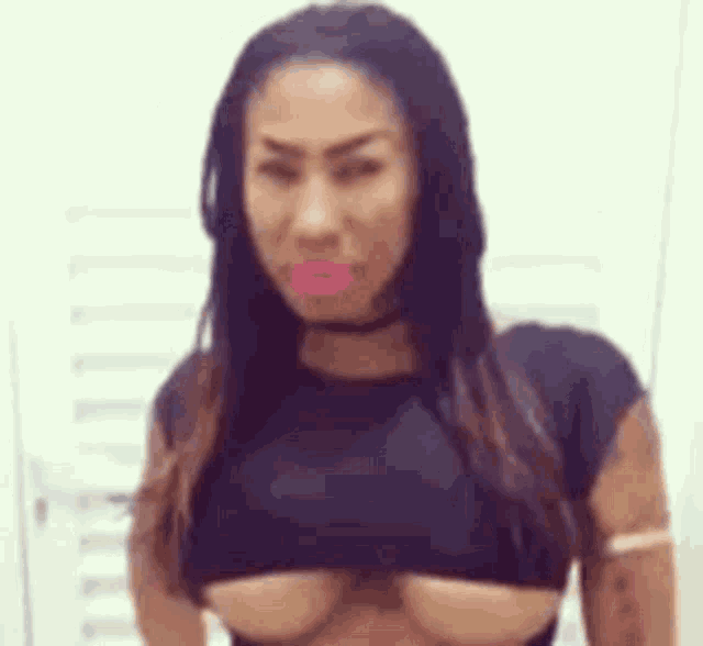 a woman wearing a black crop top with a choker around her neck is standing in a room .
