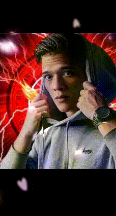 a young man wearing a grey hoodie and a watch is adjusting his hood