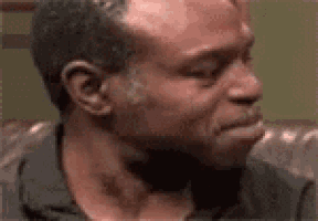 a man is sitting on a couch with his eyes closed and crying .