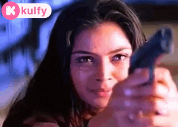 a woman is pointing a gun at the camera with a kulfy logo in the background .