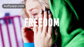 a woman in a green hoodie is covering her face with her hands and the word freedom is written above her .