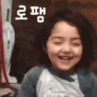 a little girl is smiling with her eyes closed and a fan in the background