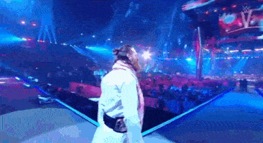 a man in a white robe is standing on a stage in front of a crowd of people .