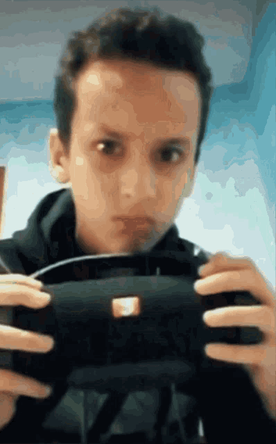 a young boy is holding a black object in his hands