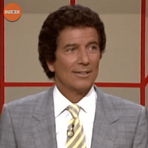 a man in a suit and tie is smiling in front of a buzzr sign