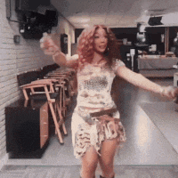 a woman with red hair is dancing in a room with chairs