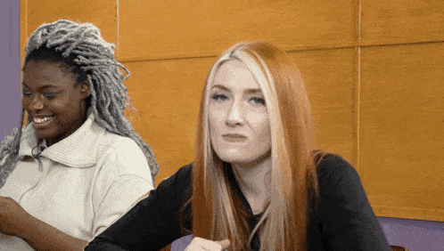 a woman with red hair is sitting next to a woman with dreadlocks