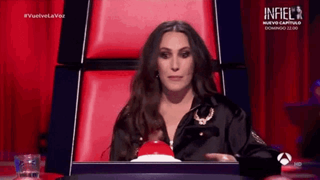 a woman is sitting in a red chair with a red button in front of her