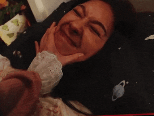 a woman is laying on a bed with a pillow with planets on it