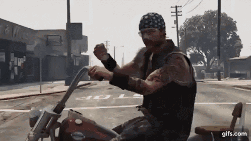 a man in a bandana is riding a motorcycle down a street ..