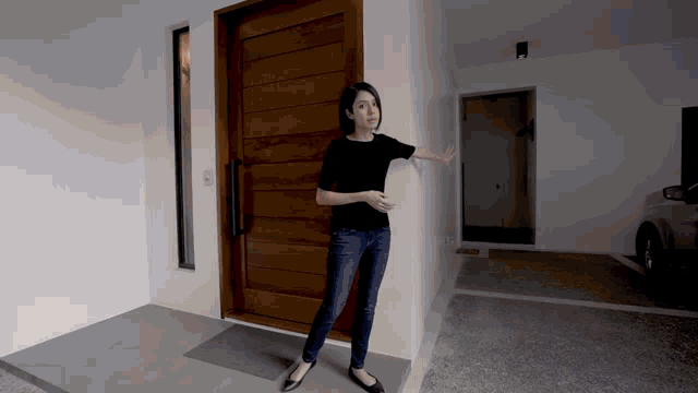 a woman in a black shirt is standing in front of a large wooden door