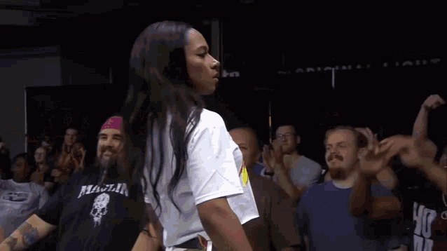 a woman in a white shirt is dancing in front of a crowd wearing a shirt that says peace