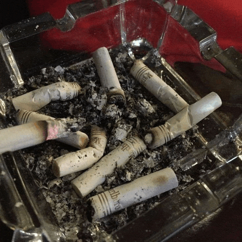 a glass ashtray filled with cigarette butts that say marlboro