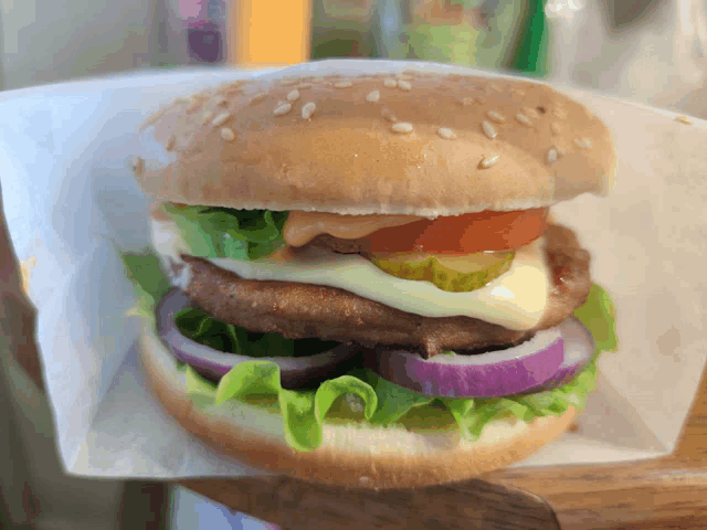 a close up of a hamburger with lettuce tomato pickles onions and cheese
