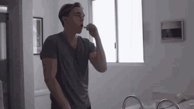 a man is brushing his teeth in front of a window
