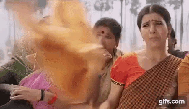 a woman in a saree is standing in front of a group of people .
