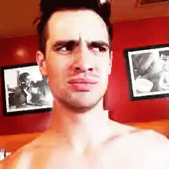 a shirtless man is making a face in front of a red wall