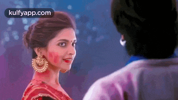 a man and a woman are looking at each other and the woman is wearing a red saree .