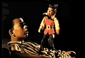 a boy is looking at a puppet that is standing next to him