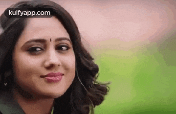 a close up of a woman 's face with a bindi on her forehead smiling .
