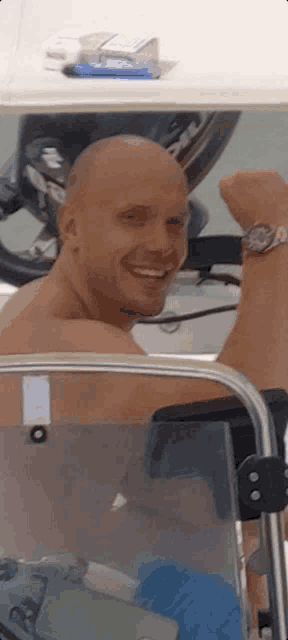 a man without a shirt is sitting on a boat with his fist in the air