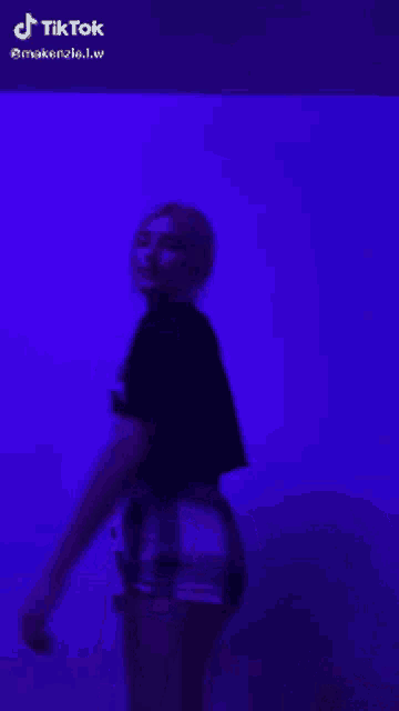 a woman is dancing in front of a purple wall with tik tok written on the bottom