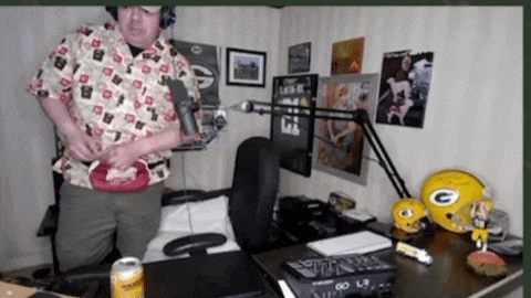 a man stands in front of a microphone in a room with a green bay packers helmet