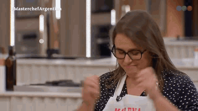 a woman wearing glasses and an apron that says masterchef argentina on it