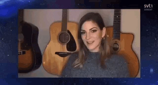 a woman is sitting in front of a wall of guitars with svt1 written on the bottom