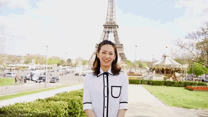 a woman is standing in front of the eiffel tower .