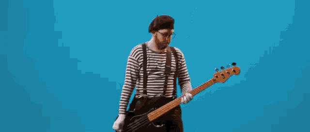 a man in a striped shirt and suspenders is playing a bass guitar .