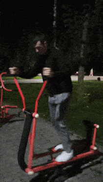 a man in a black sweater is riding a red exercise machine