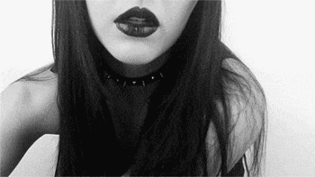a black and white photo of a woman wearing a choker necklace and black lipstick .