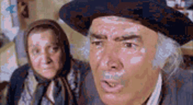 a man and a woman are standing next to each other . the man is wearing a hat .