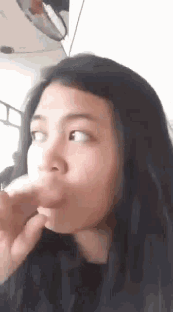 a close up of a woman making a funny face while holding her hand to her mouth .