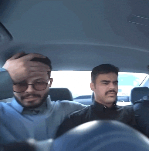 a man with glasses is holding his head while another man looks on