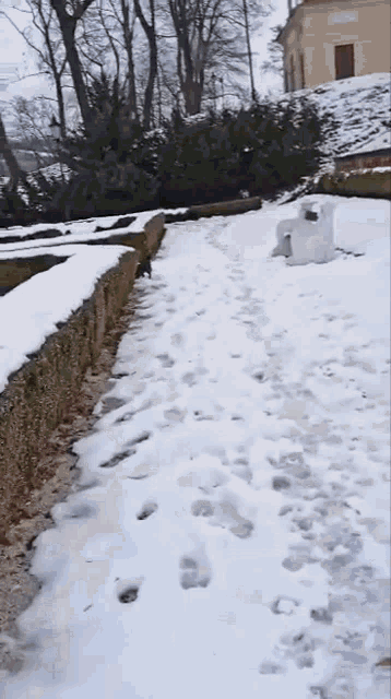 a snowy path with footprints in the snow and a building in the background