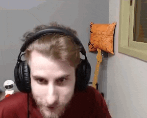 a man wearing headphones and a red shirt is looking at the camera .